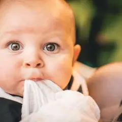 Ojos de bebés antes y después: un primer plano de un bebé con ojos curiosos y una tela blanca en la boca.