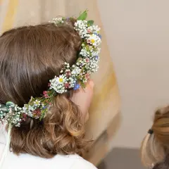 Niña con corona de flores en su cabeza, lista para su celebración de comuniones.