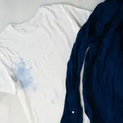 Camiseta blanca con manchas azules y camisa azul marino. Aprende como quitar el desteñido de la ropa de color.
