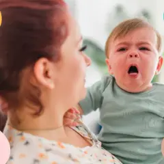 Bebé con tos, llorando en brazos de su madre.