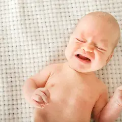 Bebé llorando, con ojos cerrados y boca abierta. Podría ser uno de los signos de deshidratación en bebés.