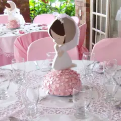 Detalle de decoración comunión niña casera con centros de mesa de comunión y mesas vestidas de rosa.