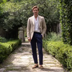 Hombre con chaqueta beige, camisa blanca y pantalón azul marino, ideal para saber como vestir para un bautizo hombre casual.
