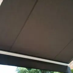 Toldo de acrílico tela oscura, con estructura blanca, protegiendo del sol.