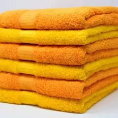 Pila de toallas suaves y esponjosas en tonos naranja y amarillo, listas para un baño reconfortante.