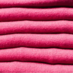 Una pila de ropa de franela rosa, suave y acogedora, lista para abrigarte.