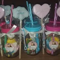 Frascos de comunión con dulces, pajitas y adornos de corazón con nombres.