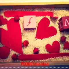 Bandeja sensorial de San Valentín para niños con corazones rojos, cubos con letras y arroz.
