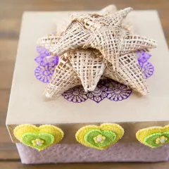Caja de regalo decorada con un lazo grande de tela, corazones y un diseño floral.