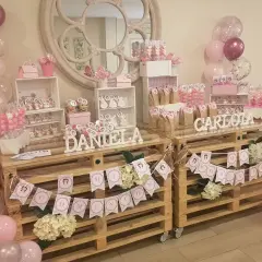 Mesa dulce casera para comunión de niña con globos rosas y blancos, dulces y decoraciones personalizadas. ¡Un festín inolvidable!