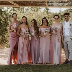 Seis damas de honor con vestidos rosas y un novio con traje claro. Un ejemplo perfecto de como vestirse para una boda de dia.