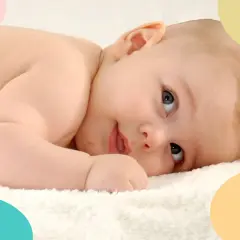 Bebé de 8 meses, en plena crisis, mira con curiosidad. Suave piel y ojos grandes sobre una toalla blanca.