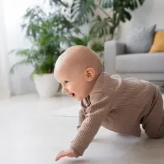 Un bebé sonriente explora el suelo, aprendiendo a gatear. ¡Una etapa emocionante cuando empiezan a gatear los bebés!
