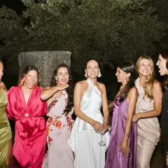 Seis mujeres posan sonrientes, luciendo vestidos elegantes, perfectos para saber como ir vestida a una boda de noche.
