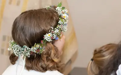 Niña con corona de flores en su cabeza, lista para su celebración de comuniones.