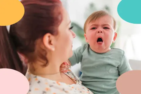 Bebé con tos, llorando en brazos de su madre.