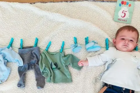 Un bebé de 5 meses celebra su mes con ropa colgada.
