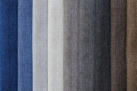 Muestras de tejido damasco en tonos azules, grises y marrones, con texturas visibles.