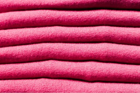 Una pila de ropa de franela rosa, suave y acogedora, lista para abrigarte.