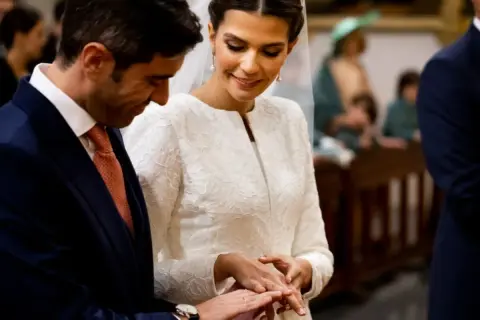 Novios intercambiando anillos de boda. Un momento tierno, como si fueran niños jugando a casarse, pero con la solemnidad del momento.