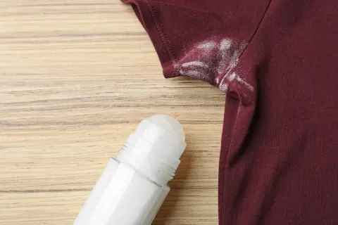 Manchas blancas de desodorante en una camiseta granate, un problema común que puede desteñir ropa.