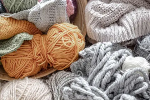 Ovillos de lana y tejidos en tonos grises, ocres y verdes. Una muestra de la suavidad y calidez que ofrece la alpaca textil.