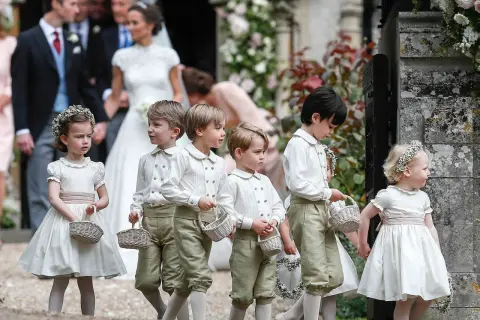 Niños y niñas con trajes de época, portando cestas, son pajes en una boda.