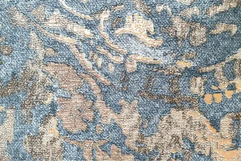 Textura de tela con patrón floral en relieve, un ejemplo de que es el jacquard, en tonos azules y beige.