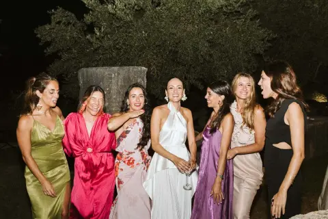 Seis mujeres posan sonrientes, luciendo vestidos elegantes, perfectos para saber como ir vestida a una boda de noche.
