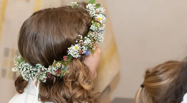 Niña con corona de flores en su cabeza, lista para su celebración de comuniones.