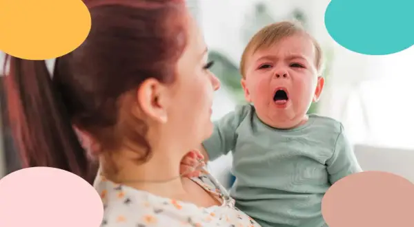 Bebé con tos, llorando en brazos de su madre.
