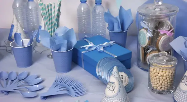 Decoración azul para un baby shower: significado de celebración y bienvenida. Vasos, platos, botellas, galletas y un regalo.