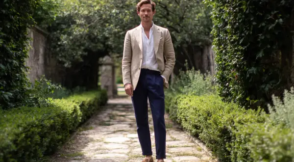 Hombre con chaqueta beige, camisa blanca y pantalón azul marino, ideal para saber como vestir para un bautizo hombre casual.
