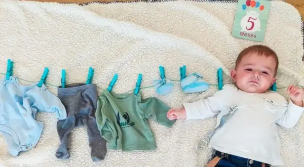 Un bebé de 5 meses celebra su mes con ropa colgada.