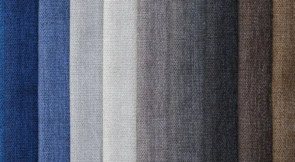 Muestras de tejido damasco en tonos azules, grises y marrones, con texturas visibles.