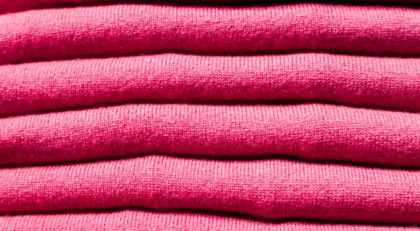 Una pila de ropa de franela rosa, suave y acogedora, lista para abrigarte.