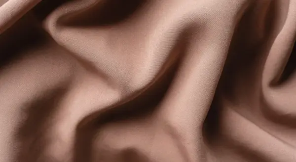 Textura de tela de satén color caramelo con pliegues suaves y sombras profundas. El satén se arruga, creando un efecto visual interesante.