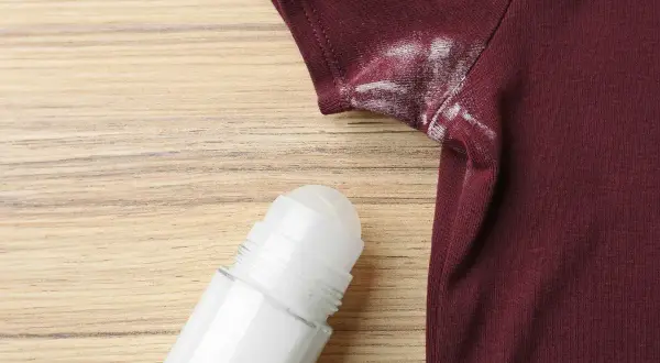 Manchas blancas de desodorante en una camiseta granate, un problema común que puede desteñir ropa.