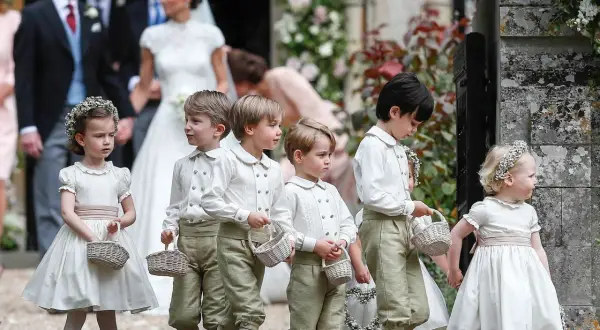Niños y niñas con trajes de época, portando cestas, son pajes en una boda.