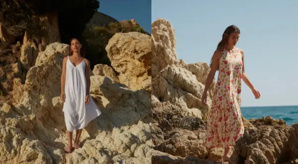 Mujer con vestido blanco de 100% viscosa y otro con estampado de coral, posando en rocas junto al mar.