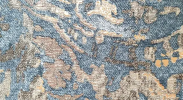 Textura de tela con patrón floral en relieve, un ejemplo de que es el jacquard, en tonos azules y beige.