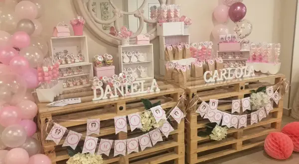 Mesa dulce casera para comunión de niña con globos rosas y blancos, dulces y decoraciones personalizadas. ¡Un festín inolvidable!