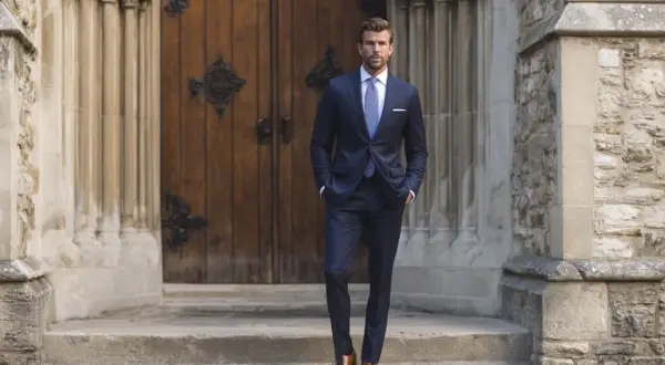 Hombre con traje azul marino, camisa blanca y corbata a cuadros, listo para saber qué hay que llevar a la iglesia para un bautizo.