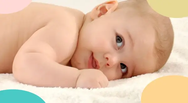 Bebé de 8 meses, en plena crisis, mira con curiosidad. Suave piel y ojos grandes sobre una toalla blanca.