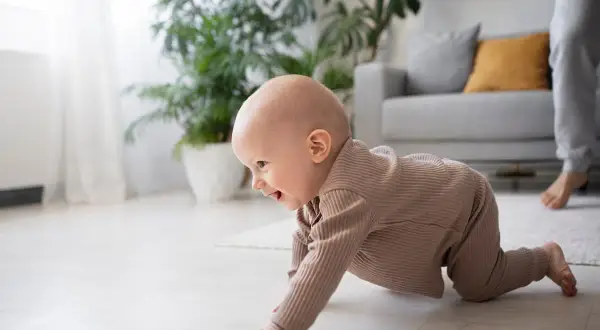 Un bebé sonriente explora el suelo, aprendiendo a gatear. ¡Una etapa emocionante cuando empiezan a gatear los bebés!