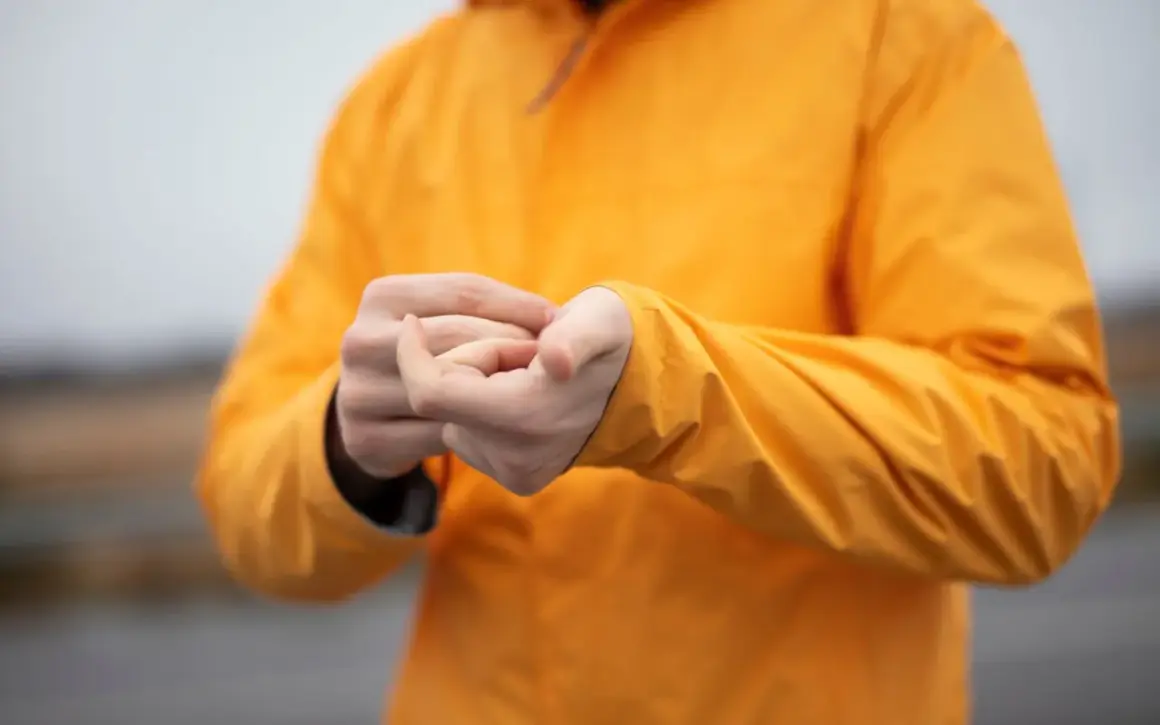 Persona ajustando la manga de su chaqueta naranja de poliéster.
