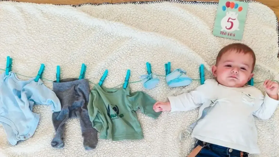 Un bebé de 5 meses celebra su mes con ropa colgada.