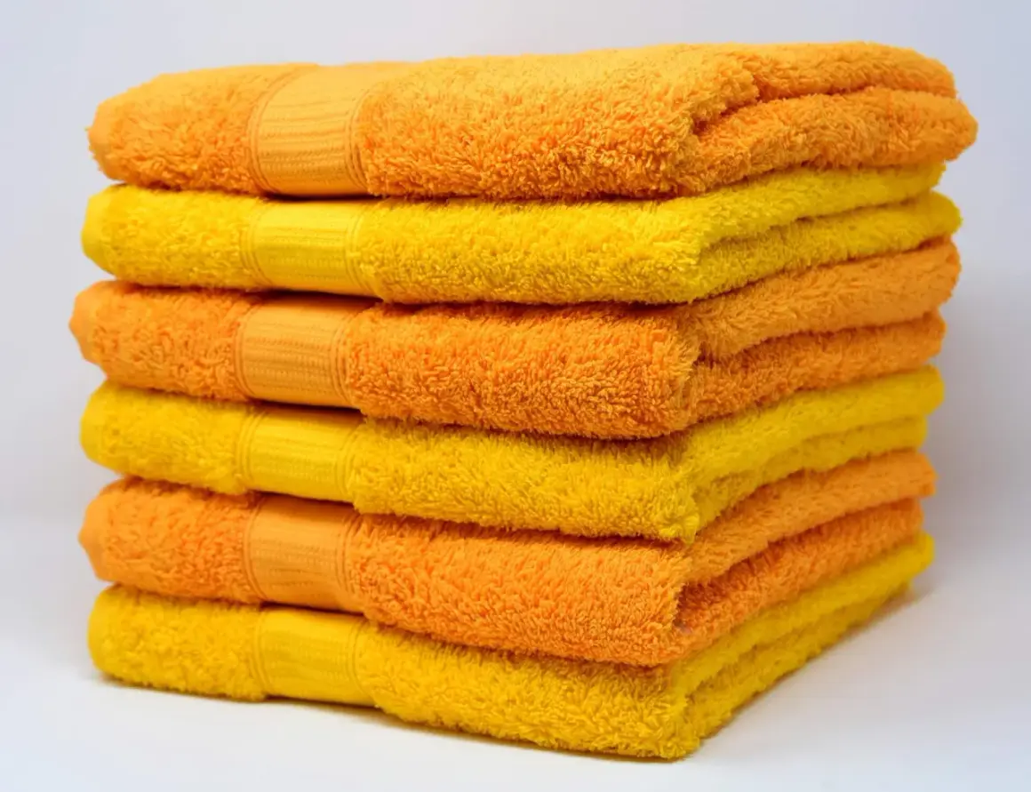 Pila de toallas suaves y esponjosas en tonos naranja y amarillo, listas para un baño reconfortante.