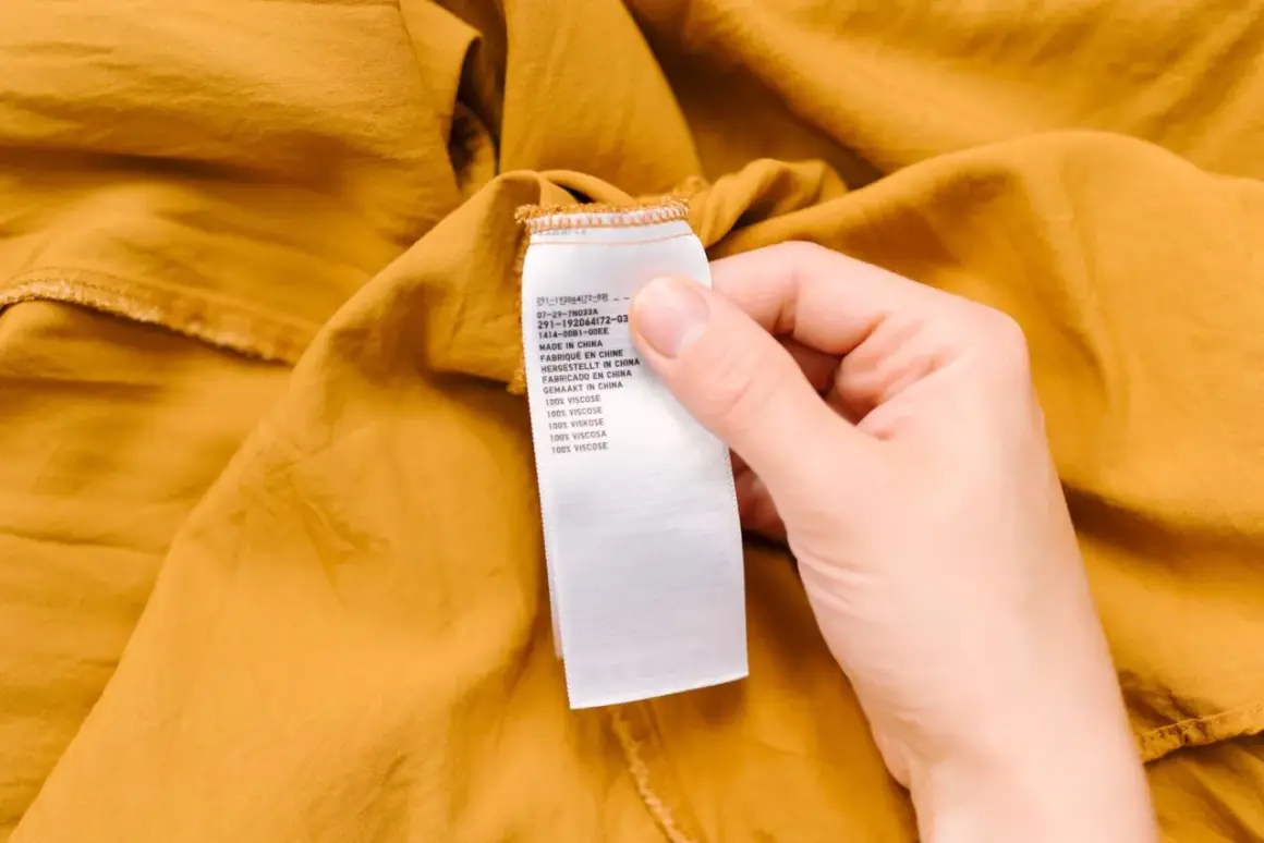 Etiqueta de cuidado de una prenda de color mostaza. Indica "100% viscosa", advirtiendo que la viscosa encoge si no se cuida.
