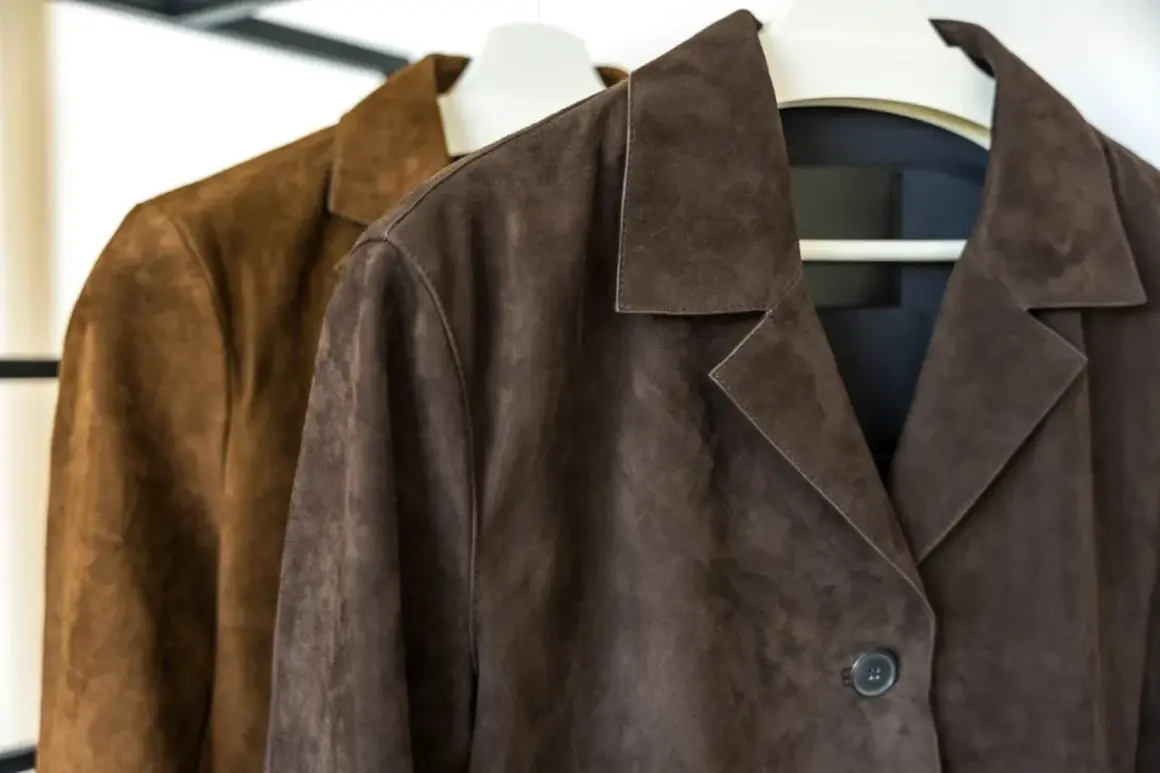 Dos chaquetas de ante, una marrón y otra café, colgadas en perchas. ¿Sabías que se puede lavar una chaqueta de ante en la lavadora?